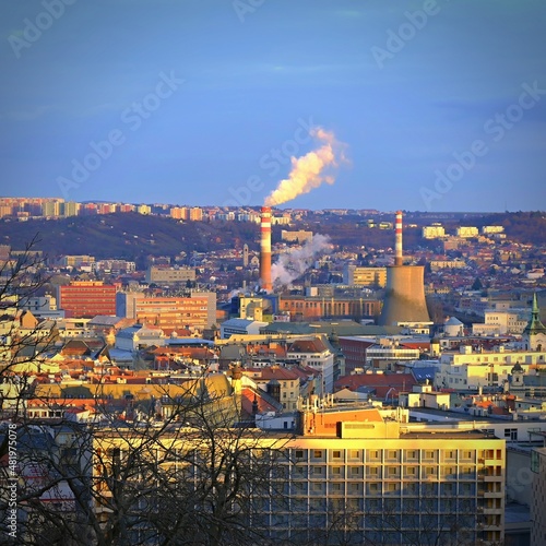 Steaming chimneys with houses in the city. Concept for environment and industry. Background with city landscape at sunset. Brno - Czech Republic - Europe.