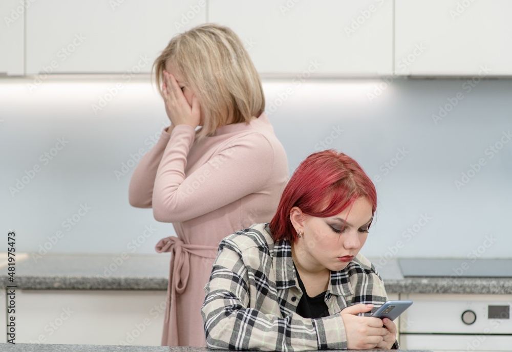 Teen girl uses smartphone and ignores her crying mother. Family relationships Teen girl uses smartphone and ignores her crying mother. Family relationships