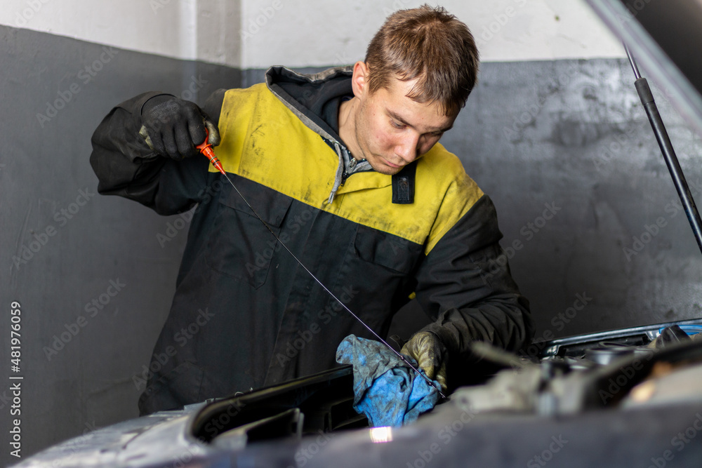 Young mechanic checking the oil level in the engine Young mechanic checking the oil level in the engine