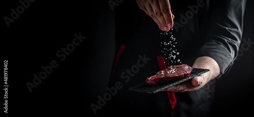 Foto Chef hands cooking meat steak and adding seasoning in a freeze motion