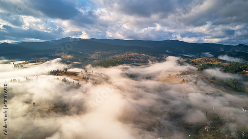 Obraz na płótnie Colorful autumn morning over foggy mountain valley. Village covered by low clouds. Fall rural landscape. Misty cold November morning w salonie