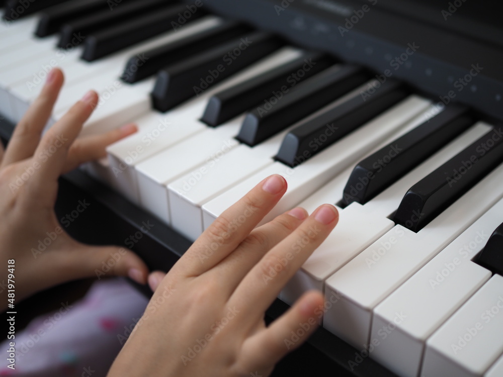 Fototapeta premium Close-up of a child's hand playing the piano . Favorite classical music. musical instruments for teaching music at home. The concept of a musical instrument. Self-education.
