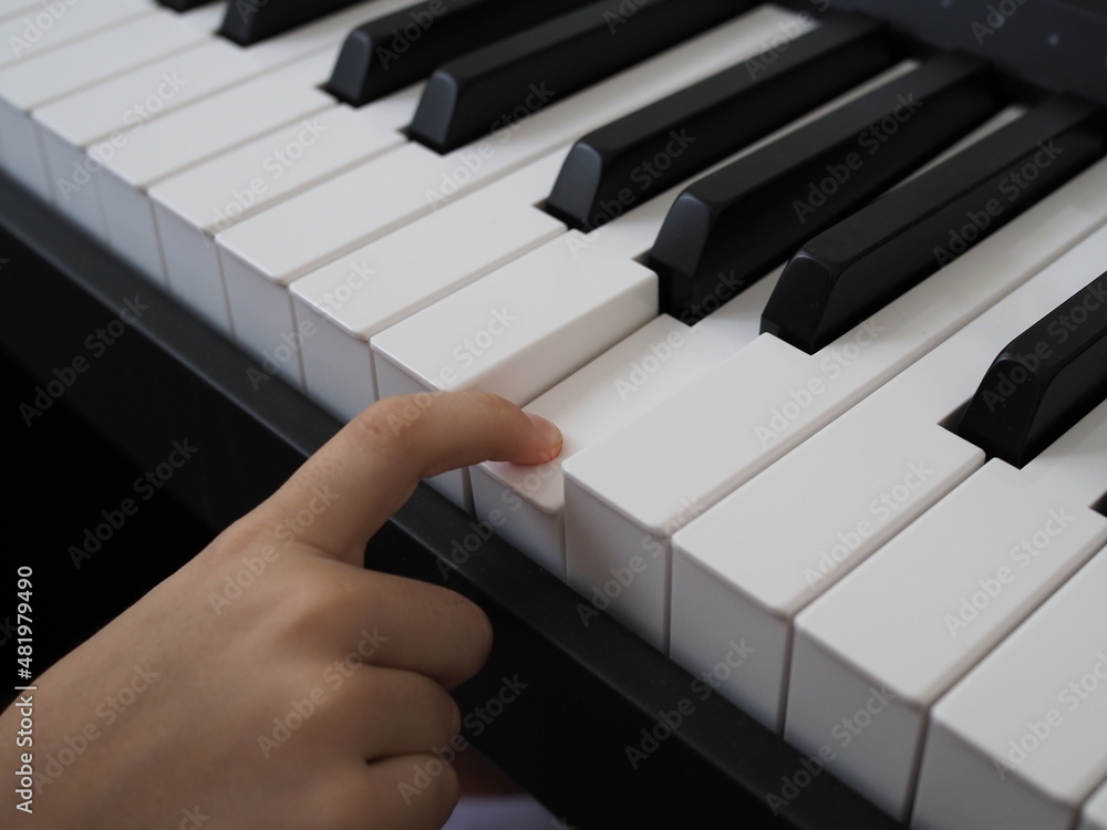 Fototapeta premium Close-up of a child's hand playing the piano . Favorite classical music. musical instruments for teaching music at home. The concept of a musical instrument. Self-education.