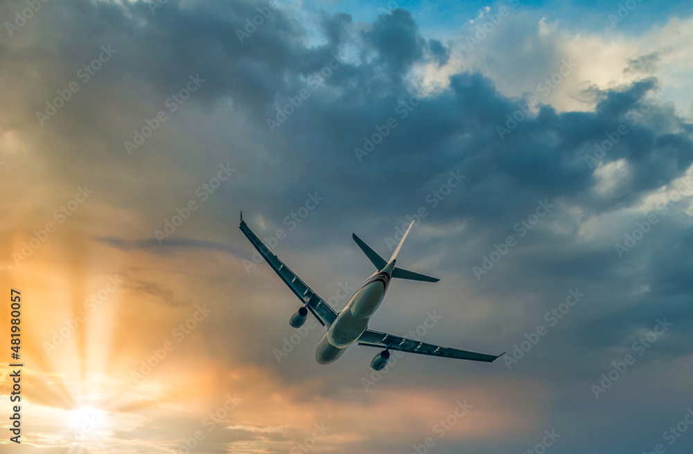 Commercial Airplane after taking off flying in the direction of sunset, cloudscape, view from low angle Commercial Airplane after taking off flying in the direction of sunset, cloudscape, view from low angle