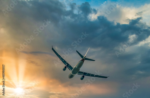 Commercial Airplane after taking off flying in the direction of sunset, cloudscape, view from low angle