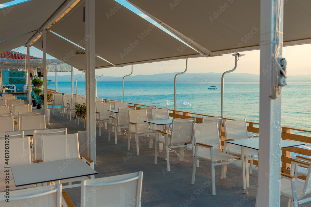 Range of wooden table and white chair for relaxation at restaurant near sea Range of wooden table and white chair for relaxation at restaurant near sea