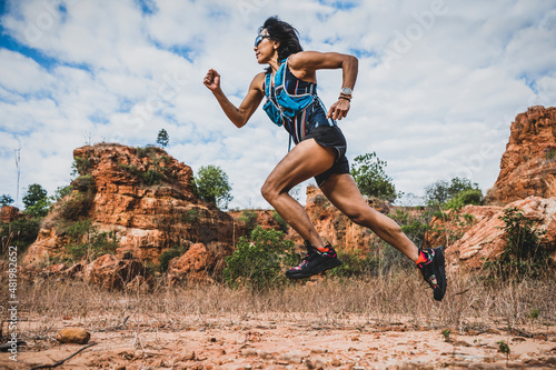 Young woman ultra trail marathon runner running through the rock mountain photo