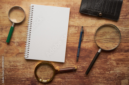 notes, trzy lupy, długopis i czarny portfel na drewnianym stole