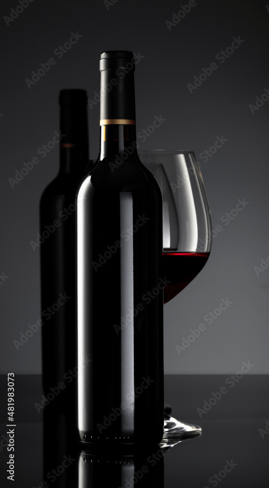 Bottle and glass of red wine on a black background. Bottle and glass of red wine on a black background.