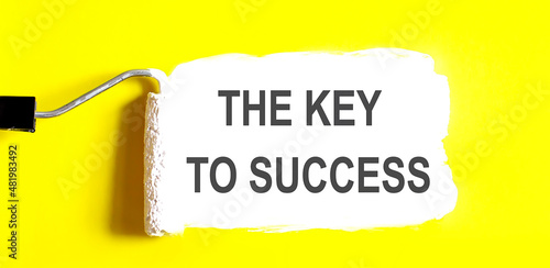 THE KYE TO SUCCESS One open can of paint with white brush on it on yellow background. Top view. photo