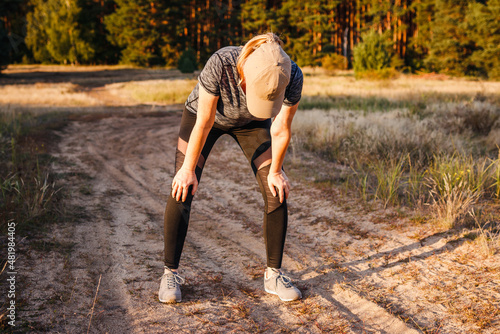 Tired woman resting after running outdoors. Female runner taking a break during jogging and fitness exercise