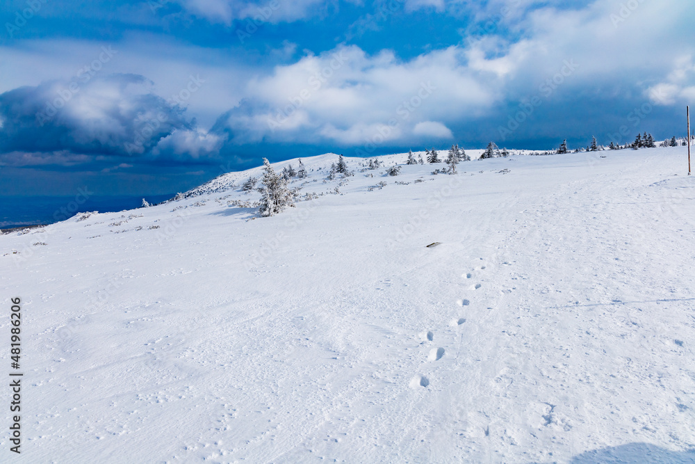 Fototapeta premium Snowy landscape of mountain trails and hills at cloudy morning