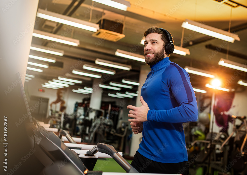 Young man in sportswear running on treadmill at gym Young man in sportswear running on treadmill at gym