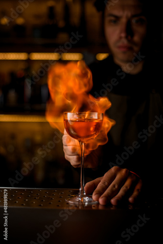 wine glass with beverage on the bar and fiery flame is in the background