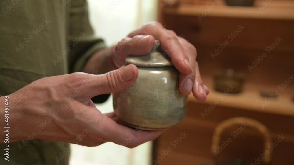 A close-up of the potter's sinewy hands showing finished teaware made by his own hands. Presentation and demonstration of Kravt production of tea ceramics A close-up of the potter's sinewy hands showing finished teaware made by his own hands. Presentation and demonstration of Kravt production of tea ceramics