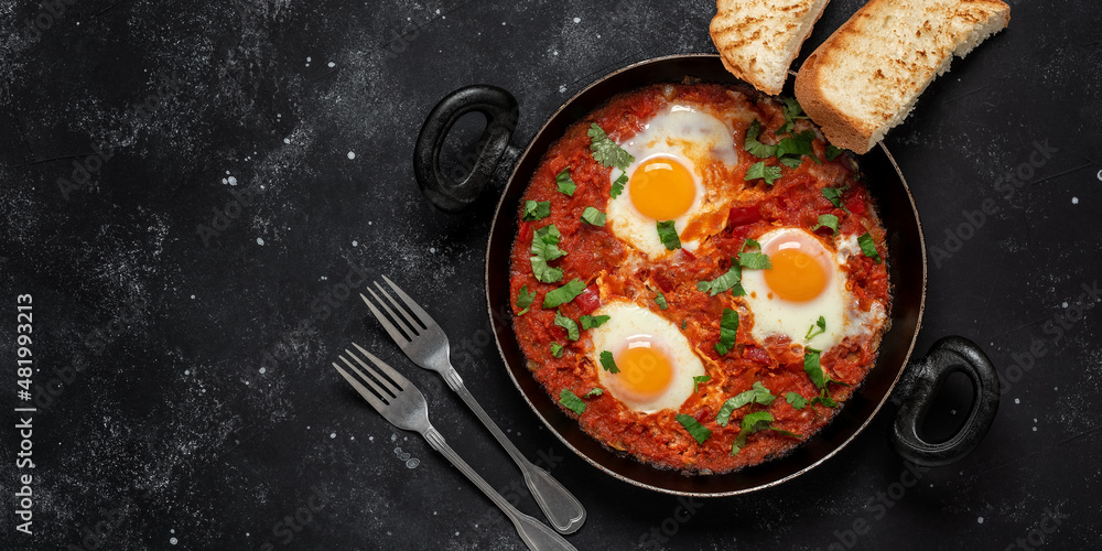 Shakshuka eggs in a pan with toast on a black concrete background