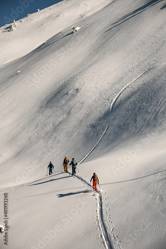 Aerial view of group of people walking at snowy trail at mountain slope photo