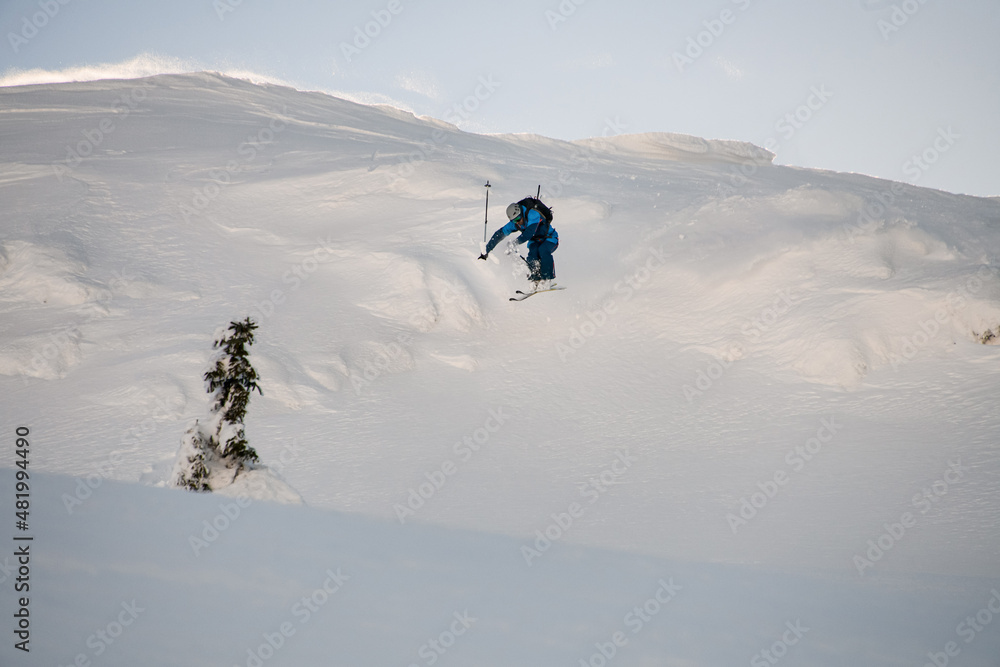 awesome view of male skier making jump while sliding down snow-covered slope on skis awesome view of male skier making jump while sliding down snow-covered slope on skis