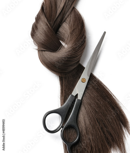 Dark brown hair strand for donation with scissors on white background