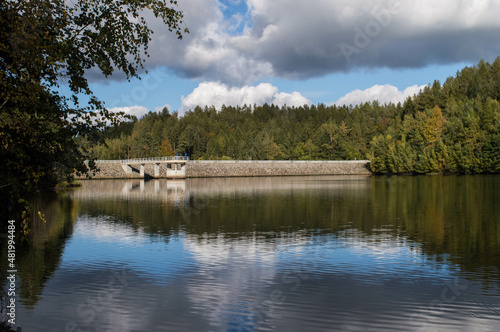 dam with blue sky and clouds on a beautiful day in fall with reflections on water