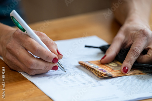 Close-up on the hand of a woman who is signing a contrac
