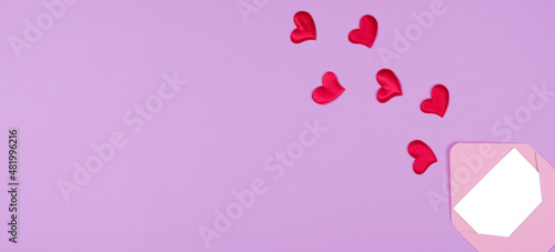 pink envelope and hearts that fly out of it on a purple background flat lay