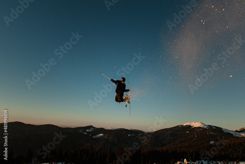 freeride skier jumps in the air against the backdrop of mountain landscape