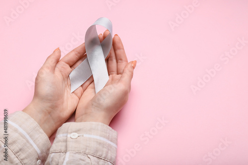Woman with Parkinson's awareness ribbon on pink background