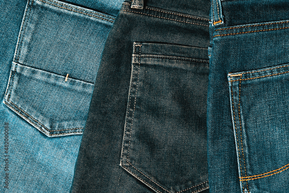 A pile of indigo jeans turned back pockets on the desk in the shop. Clothes and textile backgrounds. Warm-toned image A pile of indigo jeans turned back pockets on the desk in the shop. Clothes and textile backgrounds. Warm-toned image