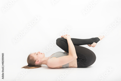Young woman does yoga with her knees to her chest. Technique of performing asanas. meditation.
