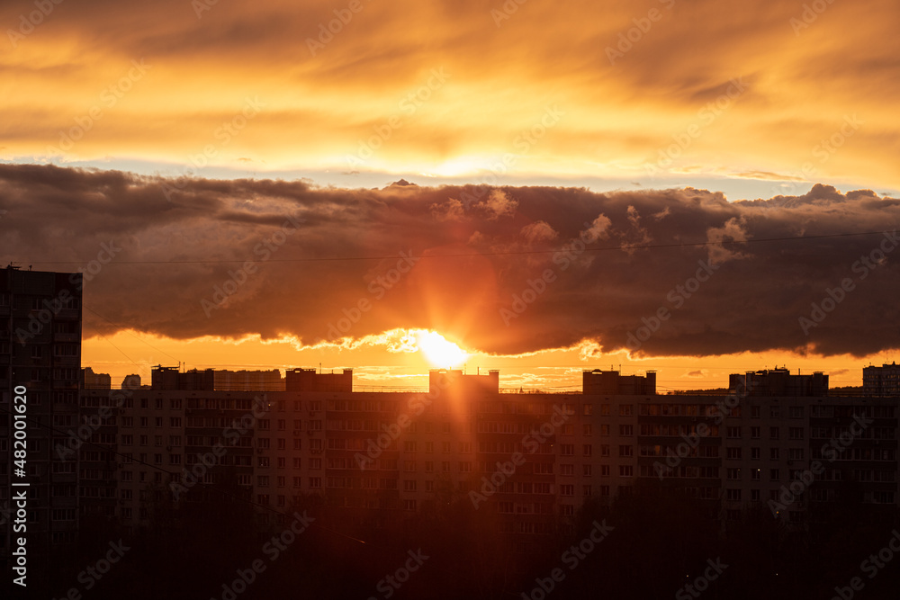 Sunset in the city of Moscow, the sun sets behind residential buildings, beautiful red clouds