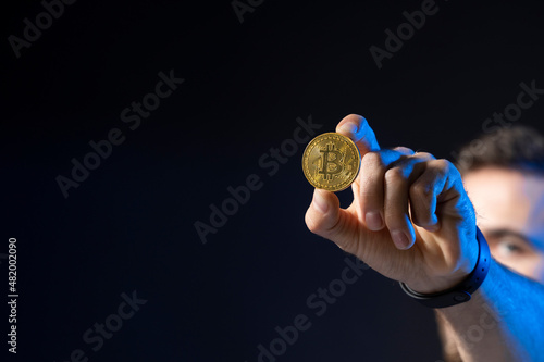 Cryptocurrency concept. Young bearded man holding virtual currency bitcoin coin. Crypto trader holding a btc coin. Cryptocurrency.