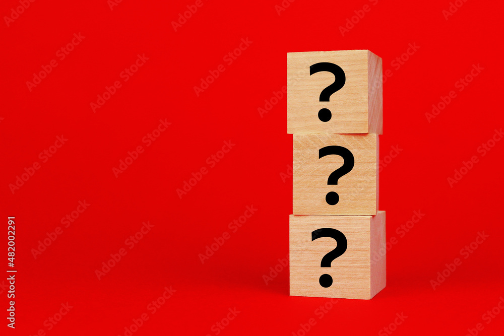 Three wooden cubes with question marks on a red background Three wooden cubes with question marks on a red background
