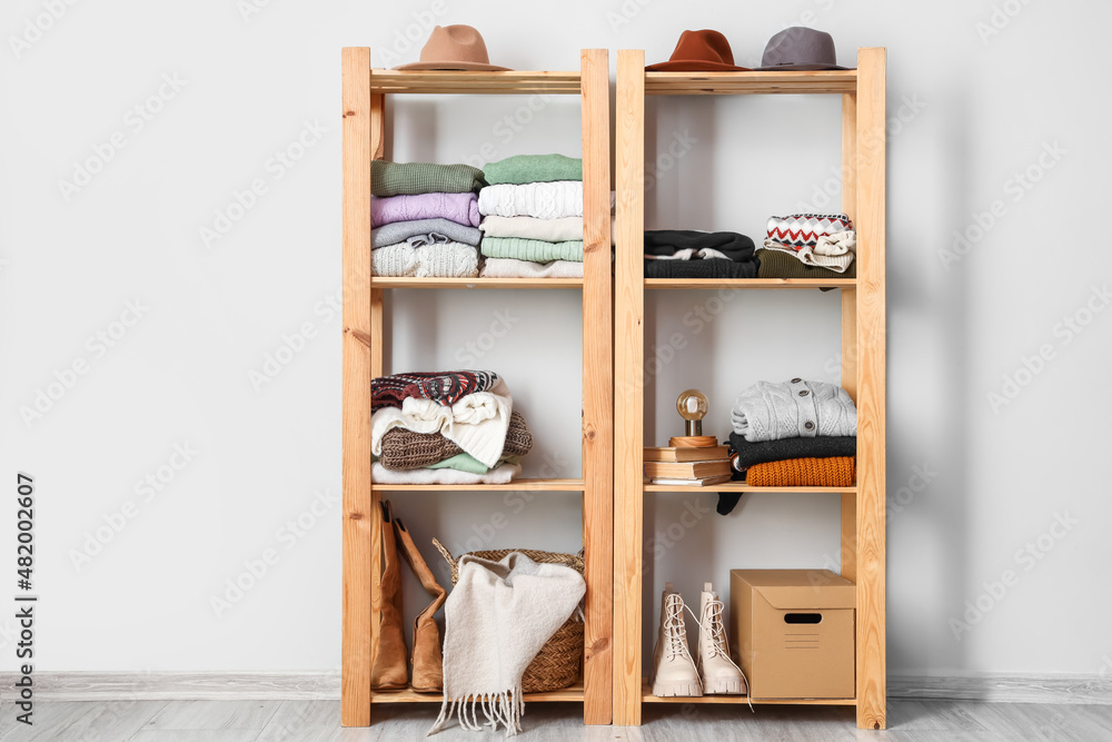 Shelving unit with warm sweaters and accessories near light wall Shelving unit with warm sweaters and accessories near light wall