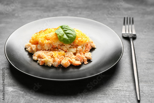 Plate with tasty English fish pie on black background