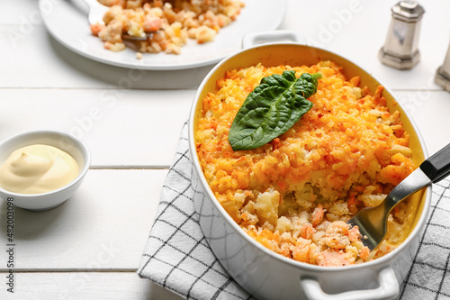Baking dish with tasty English fish pie on white wooden background