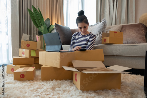 Business Start up SME concept. Young startup entrepreneur small business owner working at home, packaging and delivery situation. Women, owener of small business packing product in boxes. photo