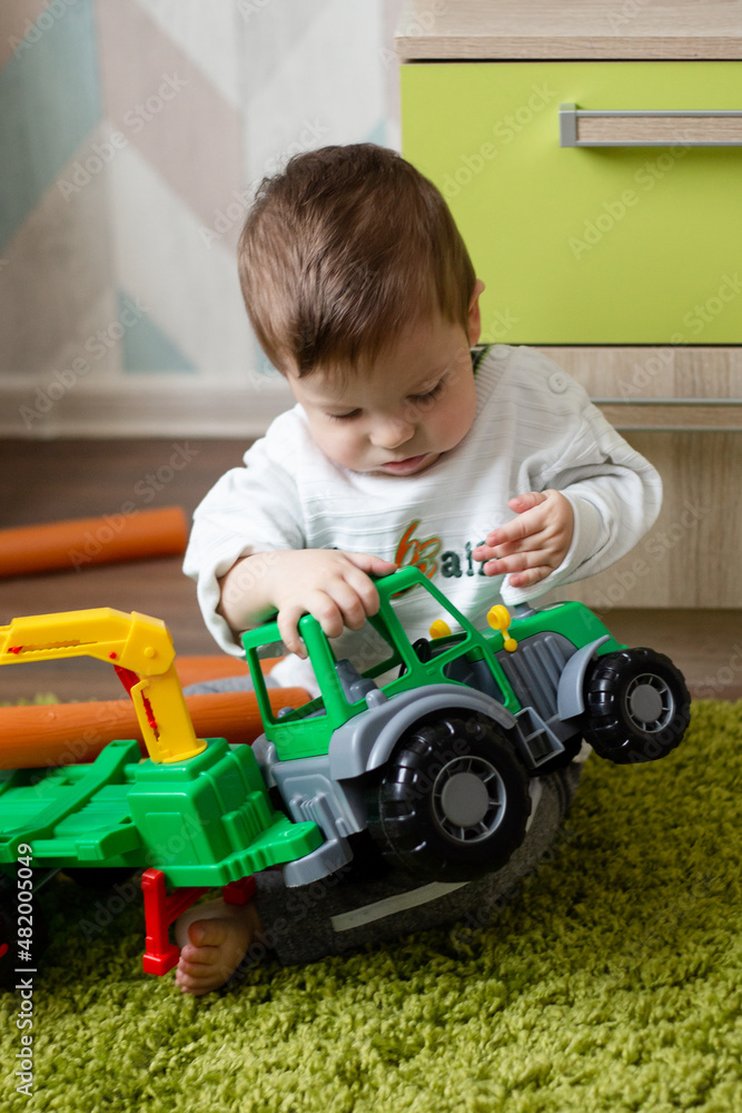 little boy playing with plastic tractor, baby playing with toy's on the floor. little boy playing with plastic tractor, baby playing with toy's on the floor.
