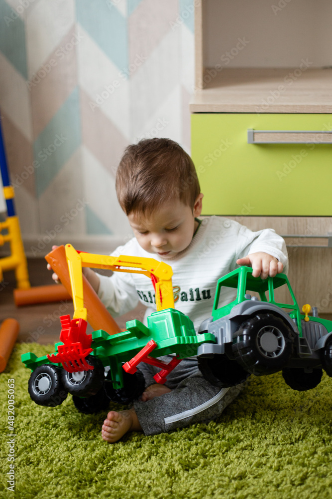 little boy playing with plastic tractor, baby playing with toy's on the floor. little boy playing with plastic tractor, baby playing with toy's on the floor.