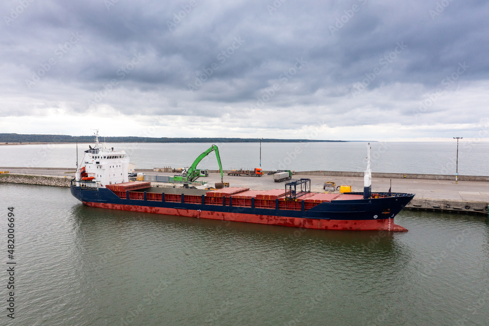 An aerial drone view of the industrial port in the Baltic Sea. There is a ships under load in the harbor. An aerial drone view of the industrial port in the Baltic Sea. There is a ships under load in the harbor.