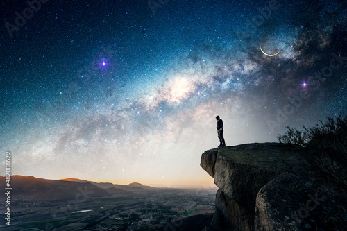 man standing on the rock outdoors  over the valley  staring the Milky Way and shooting stars