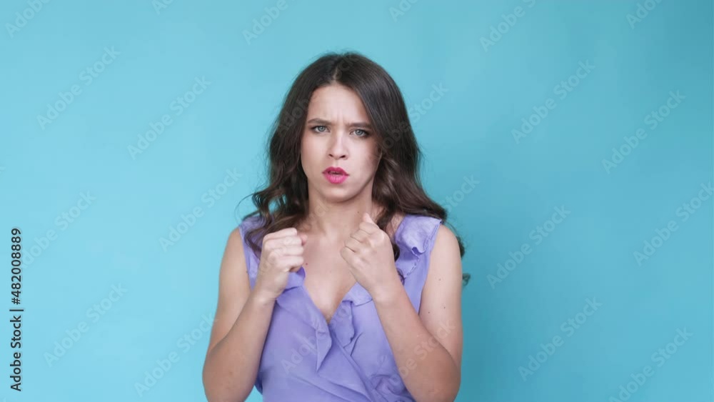 Battle woman. Meme expression. Aggressive attack. Frowning angry female boxer pretending to fight isolated blue looped video. Battle woman. Meme expression. Aggressive attack. Frowning angry female boxer pretending to fight isolated blue looped video.