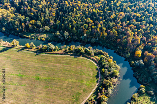 A sharp bend in a river that flows between forest and agricultural fields, aerial view