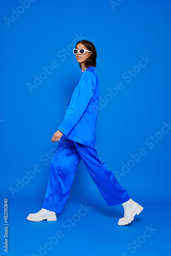 Fashion asian female model in blue suit, white boots and sunglasses.
