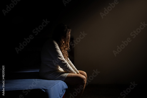 Uma mulher triste, sentada na beirada da cama, de noite. Conceito de depressão. photo