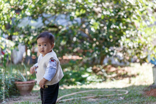 Outdoor portrait of mixed raced toddler in a garden  out of focus green leaves in the background.