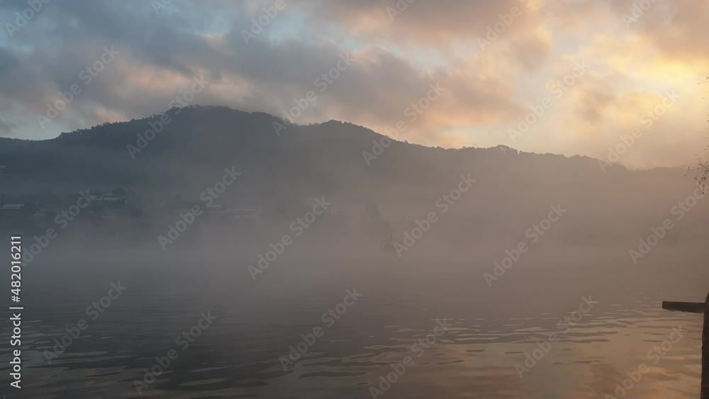 Beautiful morning sunrise with fog mist moving over lake in mountain forest Beautiful morning sunrise with fog mist moving over lake in mountain forest