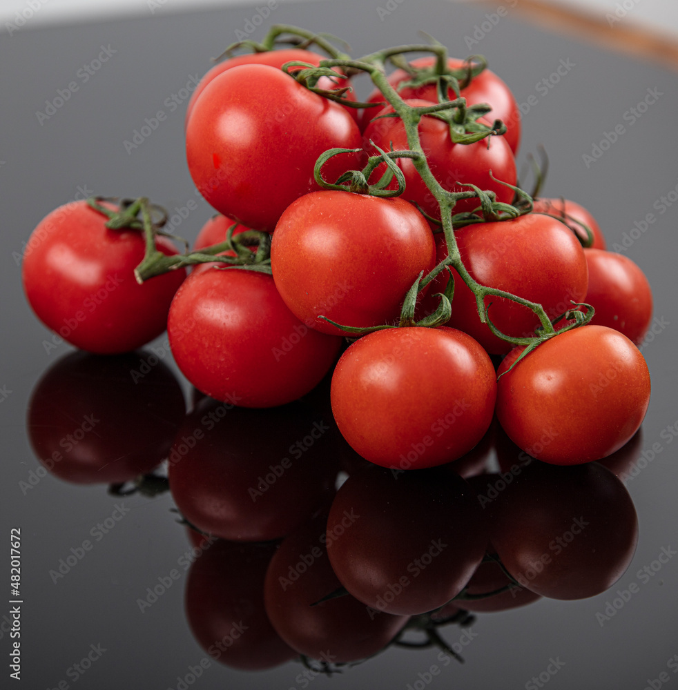 Beautiful fresh vine tomatoes (cherry) with drops of water, raw, whole and halved. On black textured slate background. Ingredients of the Mediterranean diet. Top view with copy space. Beautiful fresh vine tomatoes (cherry) with drops of water, raw, whole and halved. On black textured slate background. Ingredients of the Mediterranean diet. Top view with copy space.