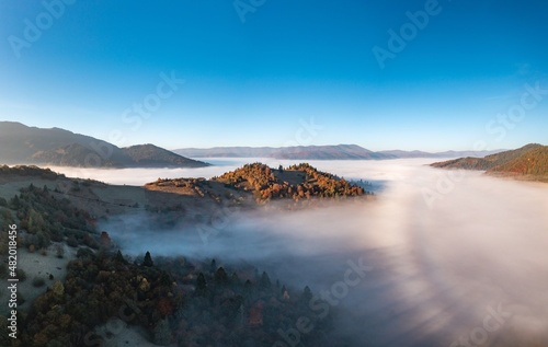 Fog among peaks of high autumn mountains with forests