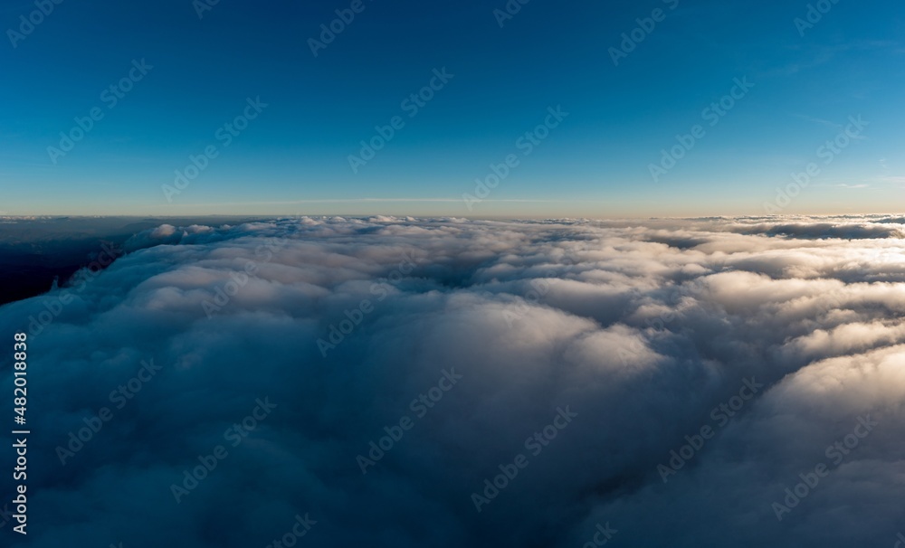 Thick layer of white clouds above mountains at sunrise